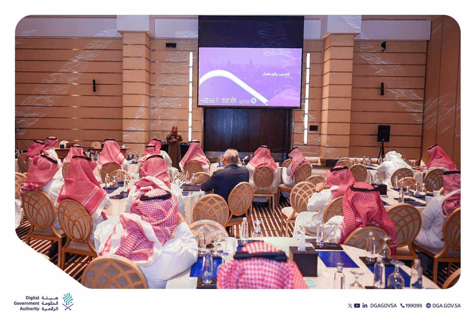 تظهر الصورة ورشة عمل نظمتها هيئة الحكومة الرقمية. يجلس المشاركون على طاولات مستديرة في قاعة كبيرة ويستمعون إلى متحدثة